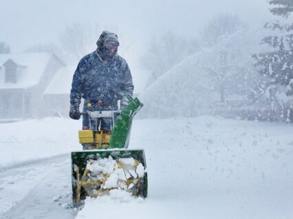 Snow blower clearing a driveway in winter
